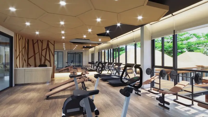 Une salle de sport lumineuse avec des équipements de fitness alignés devant de grandes fenêtres.