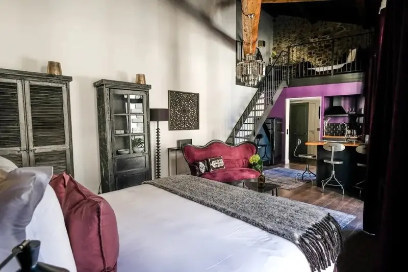 Une chambre à coucher avec un lit recouvert d'une couverture grise et des oreillers rouges.