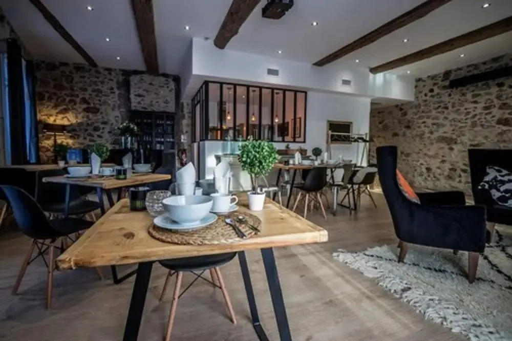 Une salle lumineuse avec des tables dressées pour le petit-déjeuner.