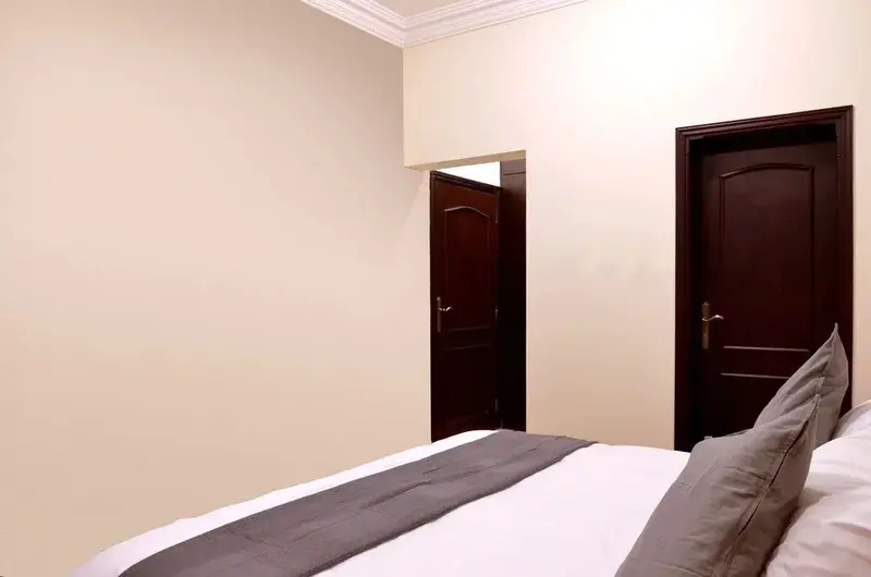 Une chambre lumineuse avec un lit fait et deux portes en bois.