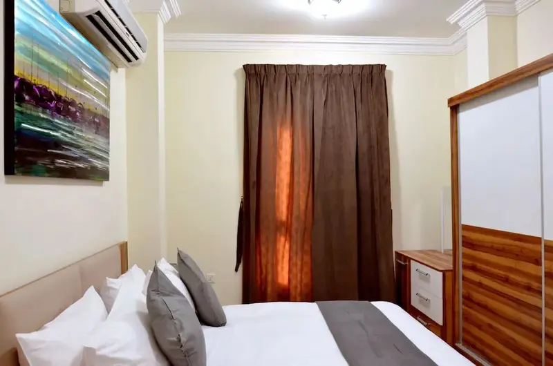 Une chambre lumineuse avec un grand lit et un tableau abstrait au mur.