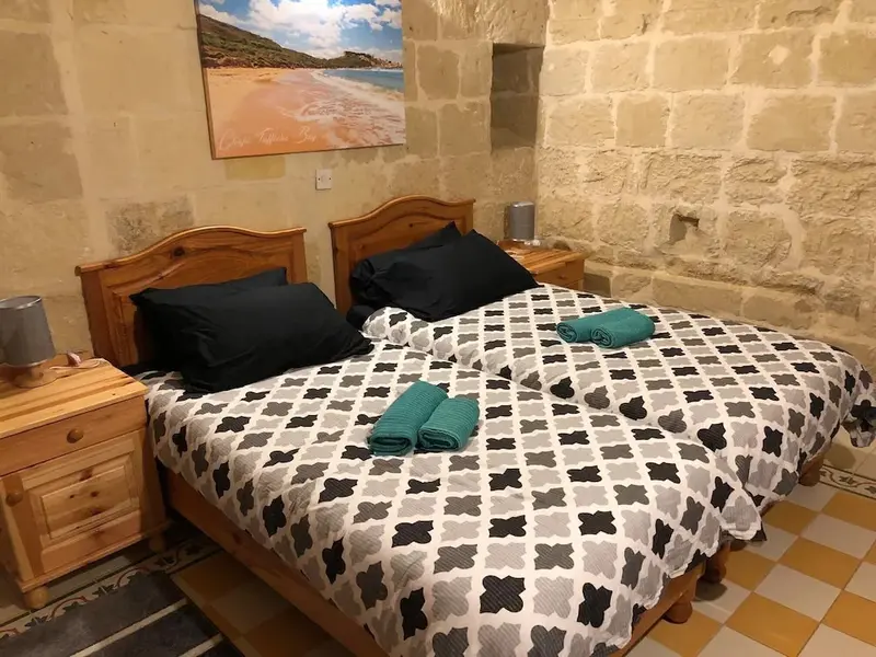 Une chambre à coucher avec un lit recouvert d'une couette à motifs et des oreillers noirs.