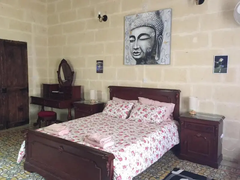 Une chambre à coucher avec un grand lit recouvert d'une couette fleurie et décorée de coussins.