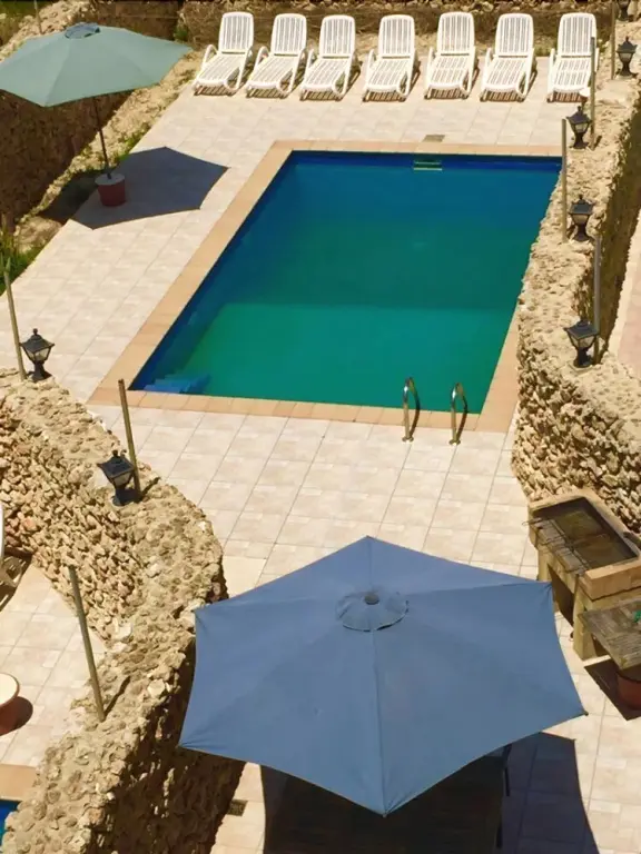 Vue aérienne d'une piscine rectangulaire entourée d'une terrasse carrelée et de transats.