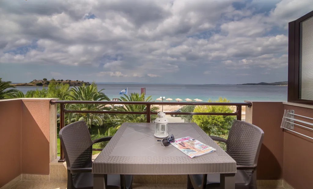 Une table et des chaises composent un espace repas sur une terrasse avec vue sur la mer.