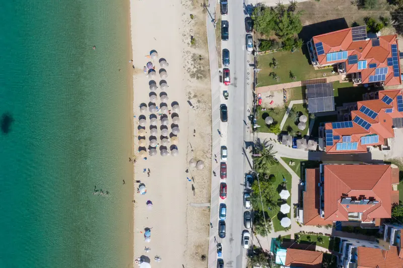 Vue aérienne d'une plage bordée de parasols et d'un complexe hôtelier.