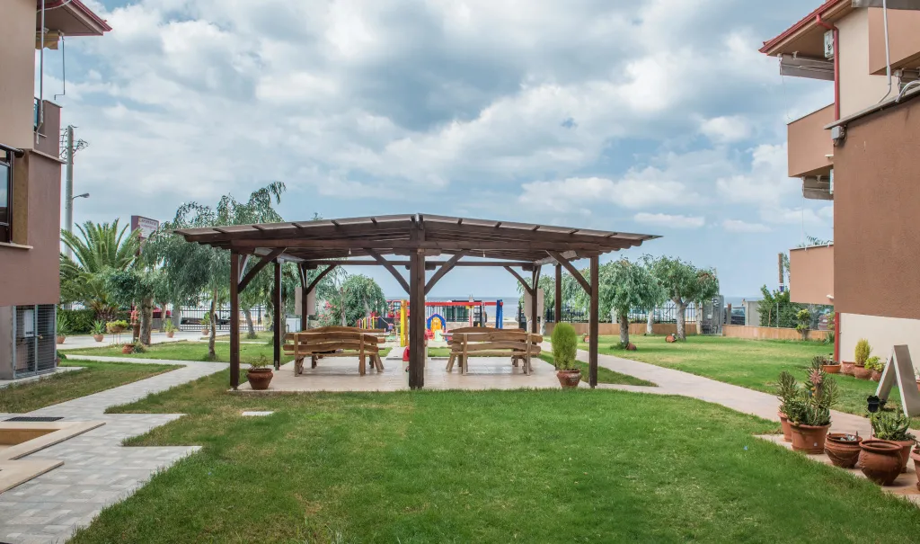 Espace extérieur ombragé avec des bancs et une aire de jeux pour enfants.