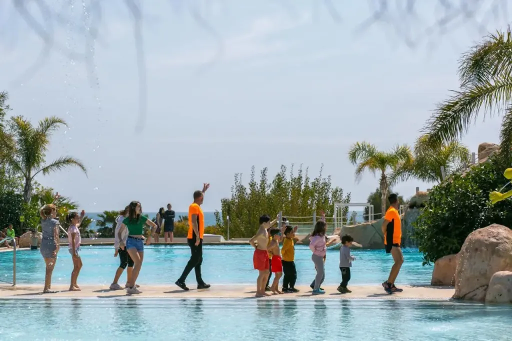 Un groupe de personnes se promène dans une piscine peu profonde avec des palmiers en arrière-plan.