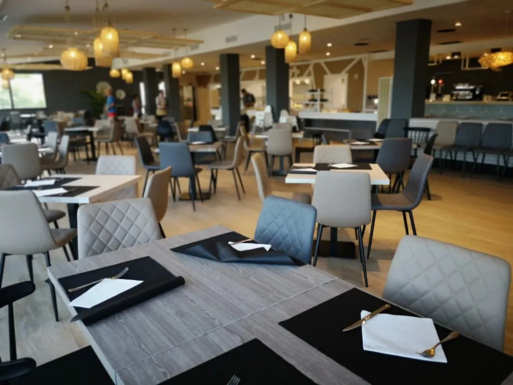 Une salle lumineuse avec des tables dressées pour le service.