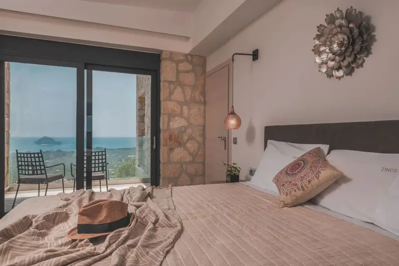 Une chambre lumineuse avec un grand lit et un accès à une terrasse offrant une vue sur la mer.
