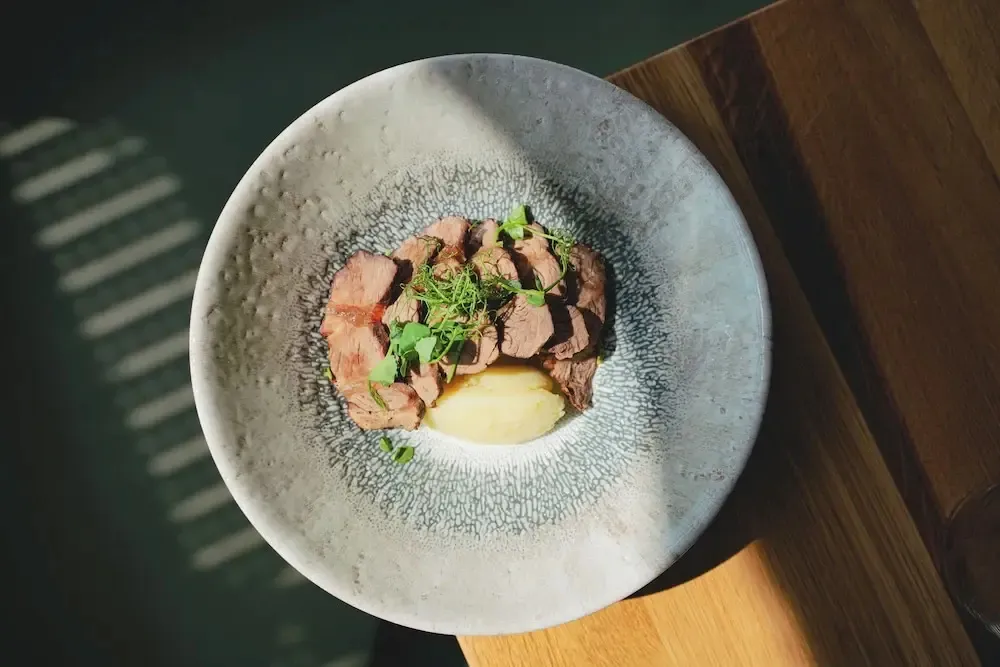 Assiette de viande accompagnée d'une purée et de verdure.