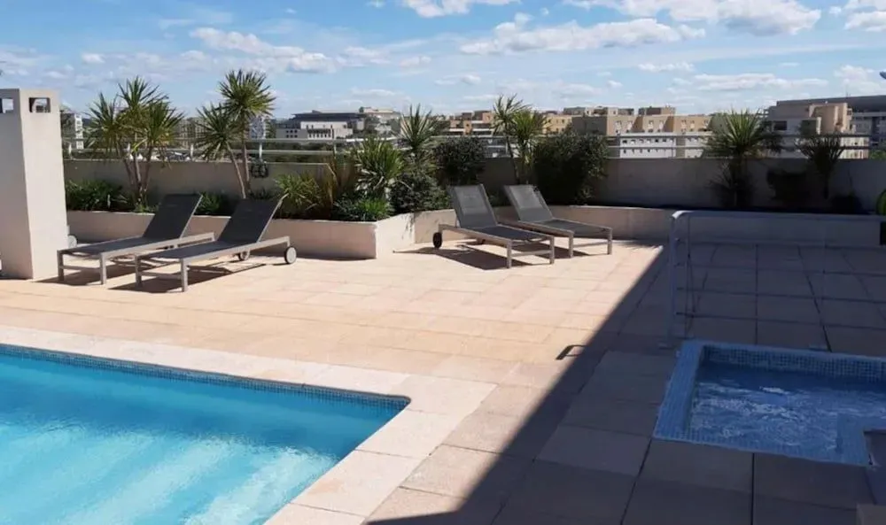 Terrasse avec transats et piscine ensoleillée.