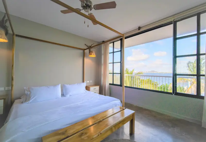 Une chambre lumineuse avec un grand lit à baldaquin donnant sur une vue sur la mer.