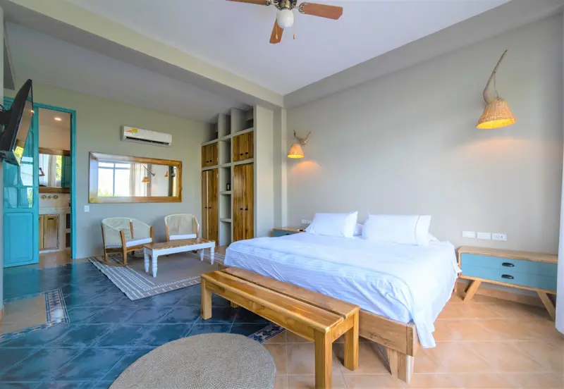 Une chambre lumineuse avec un grand lit et un coin salon.