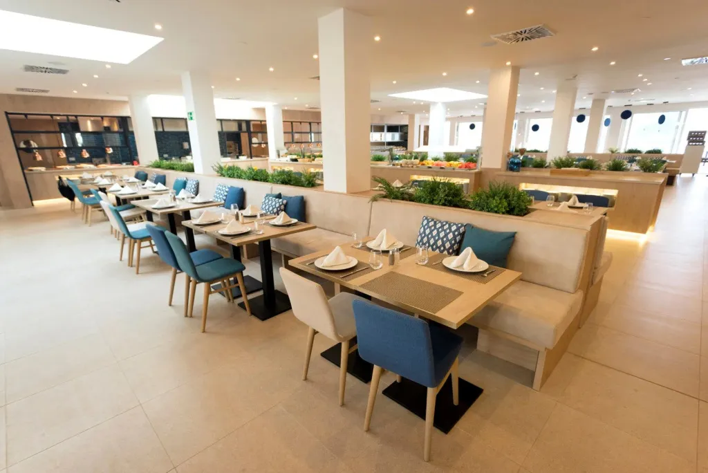 Une salle lumineuse avec des tables dressées pour le repas.