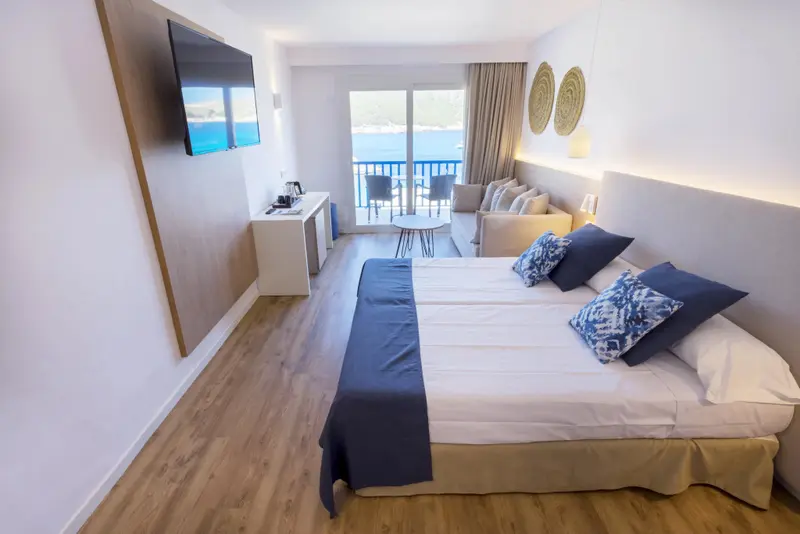 Une chambre lumineuse avec un grand lit et un accès à une terrasse vue sur mer.