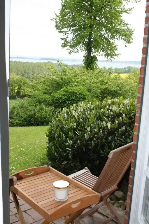 Une chaise et une petite table en bois sont posées devant une végétation luxuriante et une vue sur l'eau.