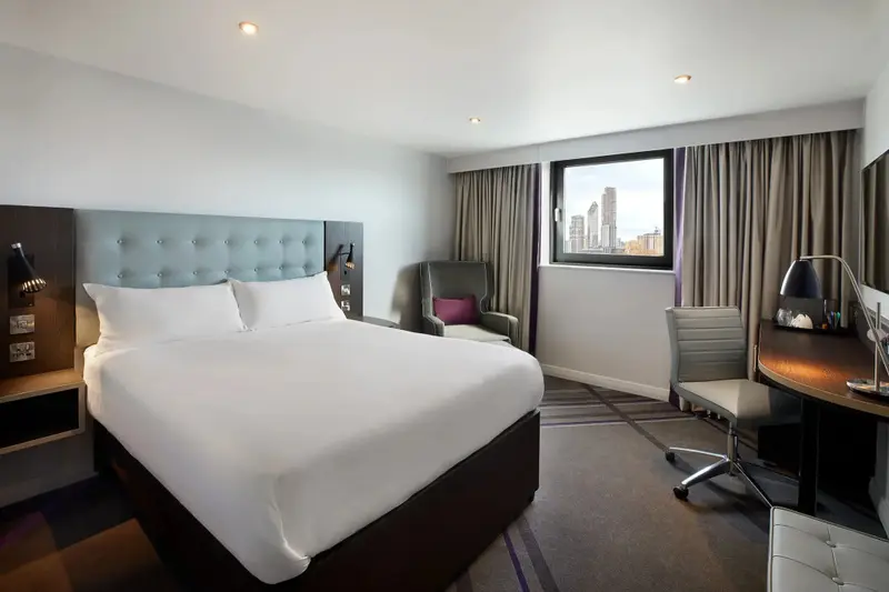 Une chambre lumineuse avec un grand lit et un espace bureau.