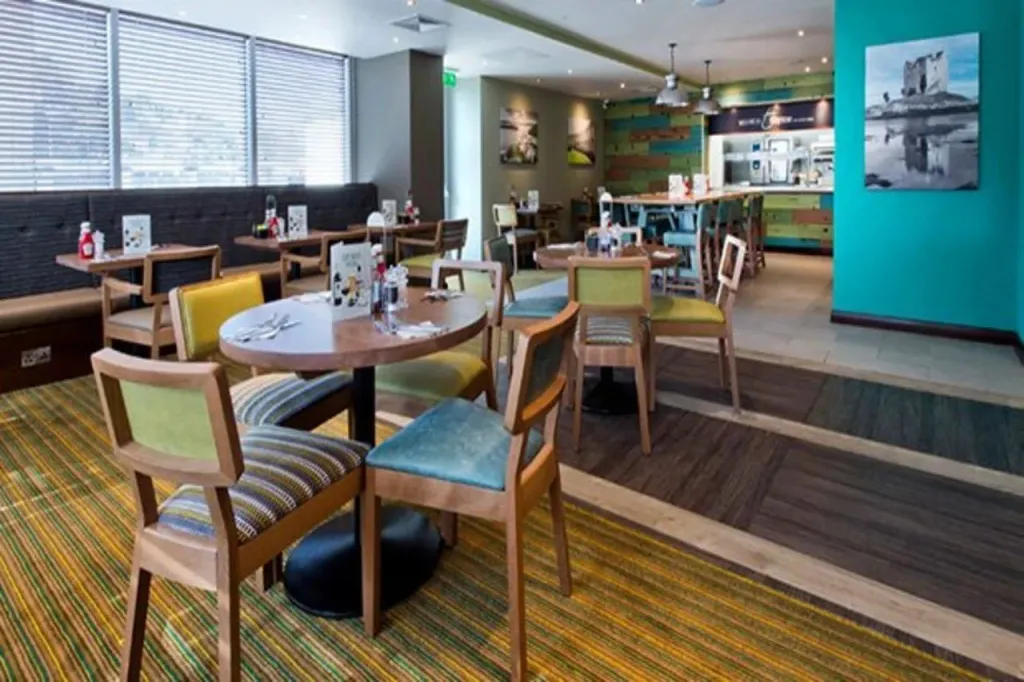 Une salle de restaurant lumineuse avec des tables et des chaises colorées.