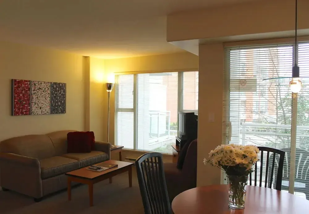 Un espace de vie lumineux avec un canapé et une table à manger près d'une grande fenêtre.