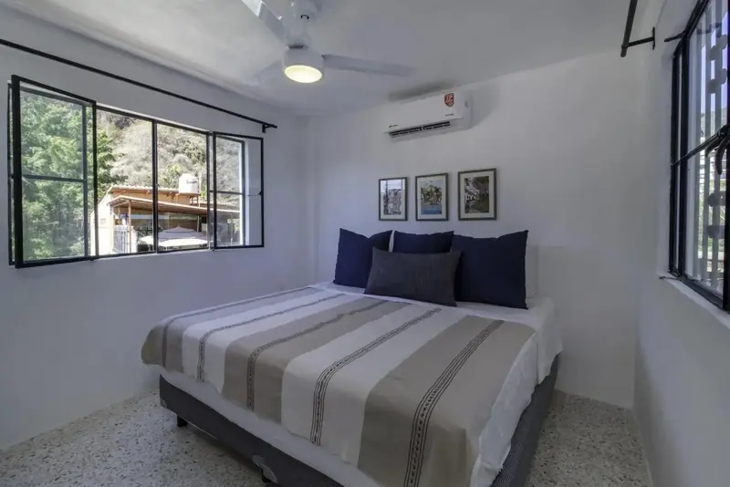 Une chambre lumineuse avec un lit double et des cadres au mur.