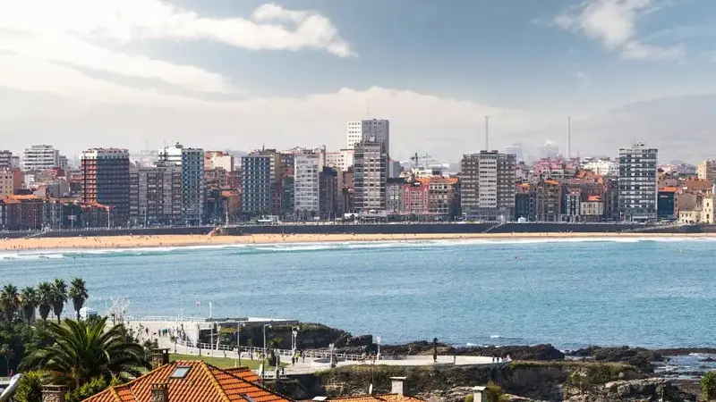 Vue d'une ville côtière avec une plage et des bâtiments alignés.