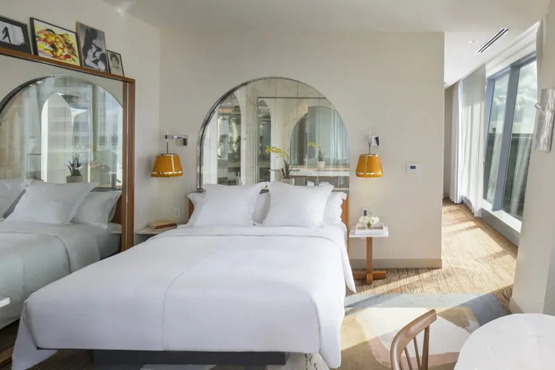 Une chambre lumineuse avec un grand lit et des miroirs en arc de cercle.
