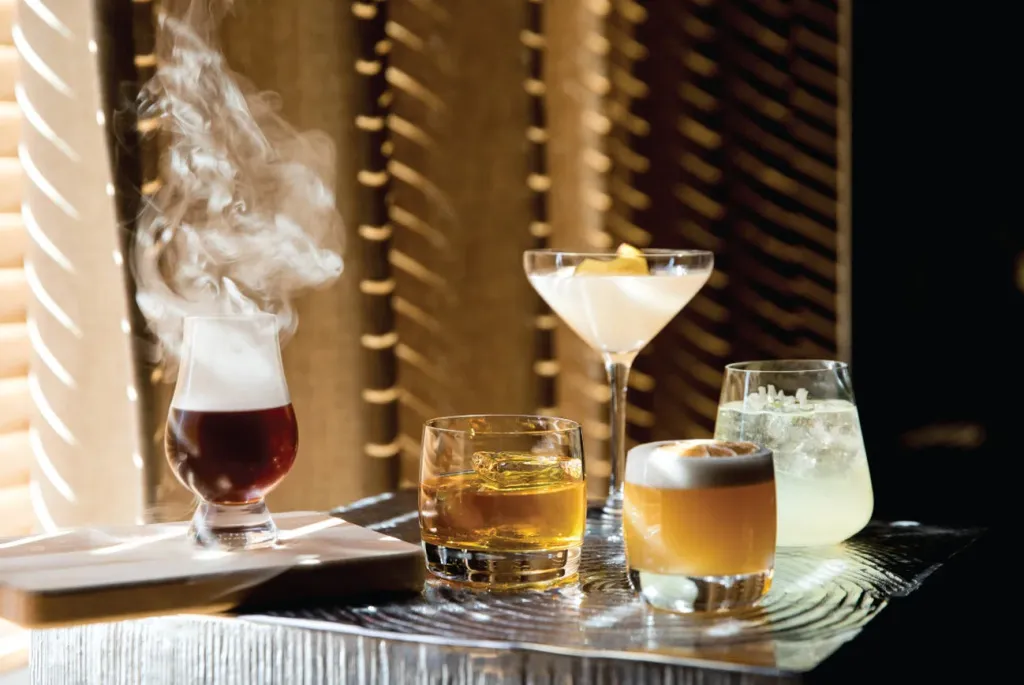 Une sélection de cocktails colorés est présentée sur un comptoir brillant.