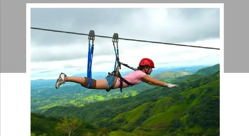 Une personne suspendue à un câble au-dessus d'un paysage montagneux verdoyant.