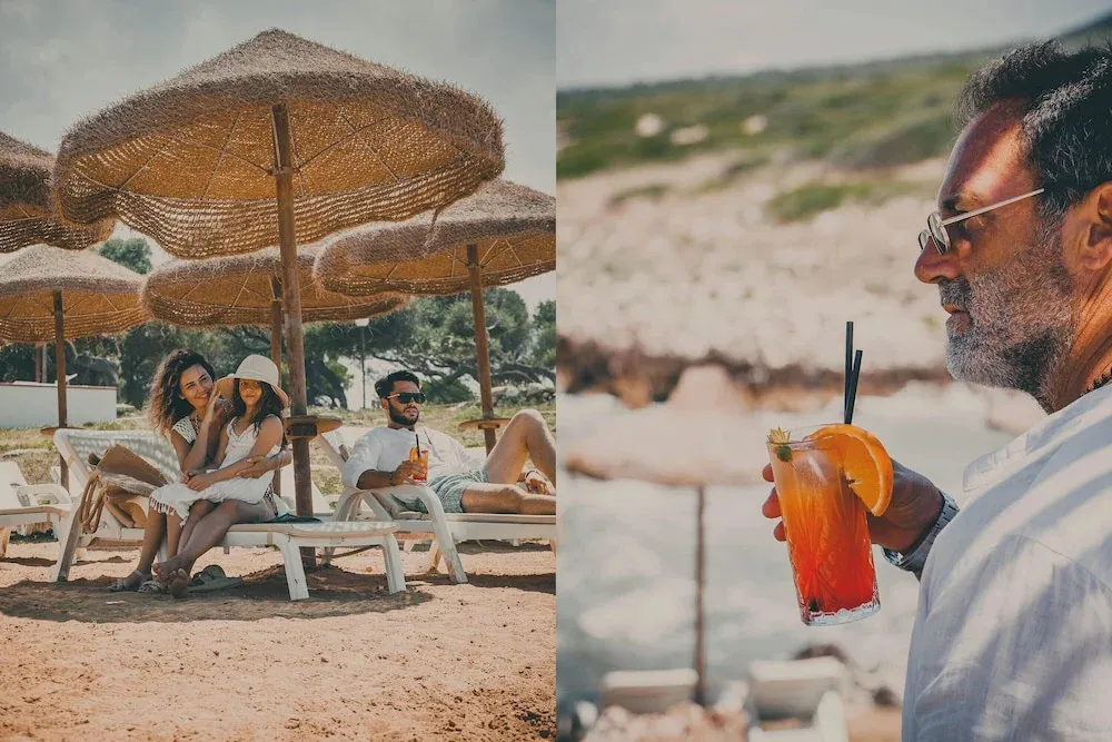 Des personnes se détendent sur des transats à l'ombre de parasols sur une plage de sable.