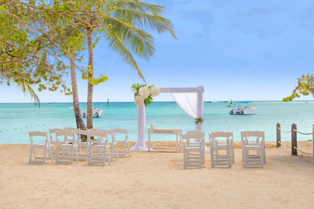 Une cérémonie de mariage est mise en place sur une plage de sable blanc face à la mer.