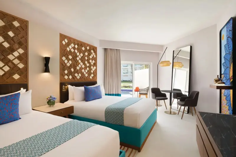 Une chambre lumineuse avec deux lits et un coin repas.
