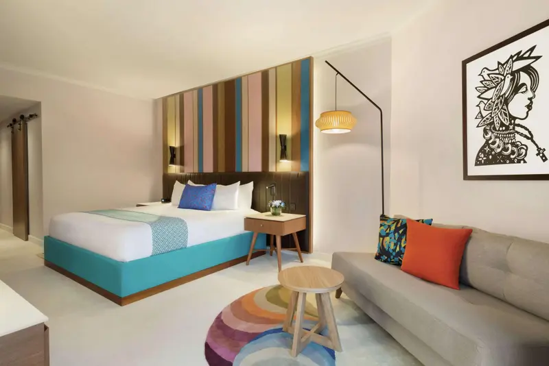 Une chambre lumineuse avec un lit double et un coin salon.