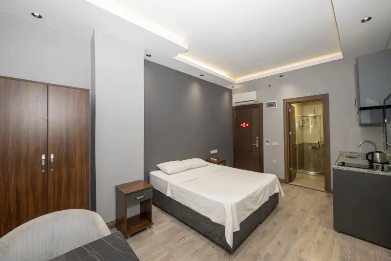 Une chambre lumineuse avec un lit simple et un coin cuisine.