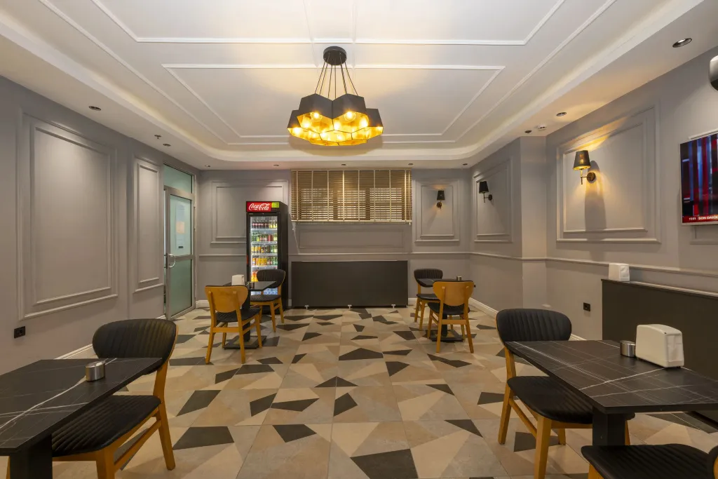 Une salle lumineuse avec des tables et des chaises est décorée de panneaux muraux et d'un lustre.