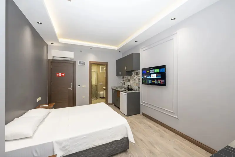 Une chambre lumineuse avec un lit et une kitchenette.