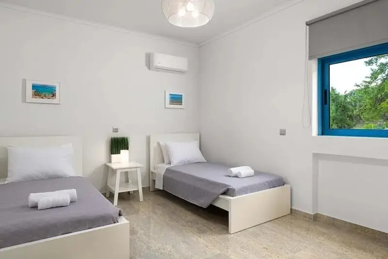 Chambre lumineuse avec deux lits simples et une fenêtre.