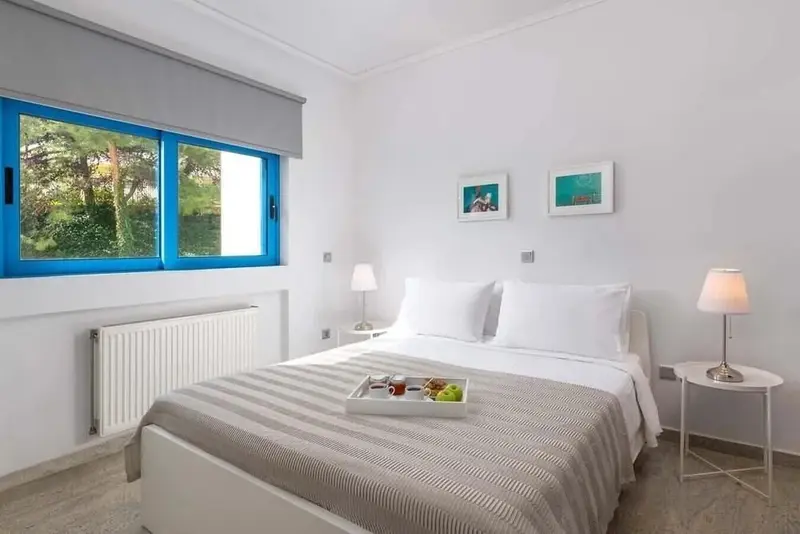 Une chambre lumineuse avec un lit double et une fenêtre ouverte sur la verdure.