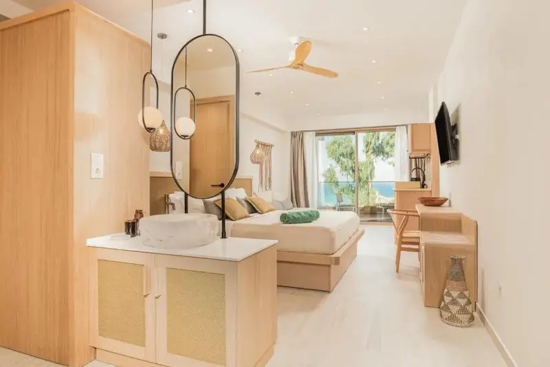 Une chambre lumineuse avec un grand lit et un accès à une vue sur la mer.
