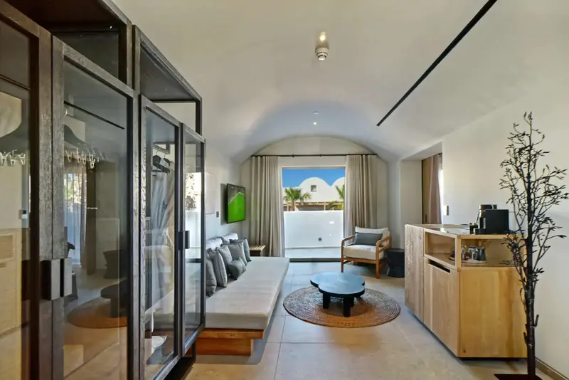 Espace de vie intérieur lumineux avec canapé et accès à une terrasse.