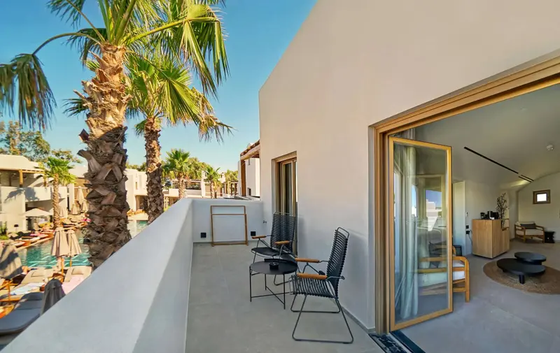 Terrasse aménagée avec mobilier d'extérieur donnant sur une piscine et des palmiers.