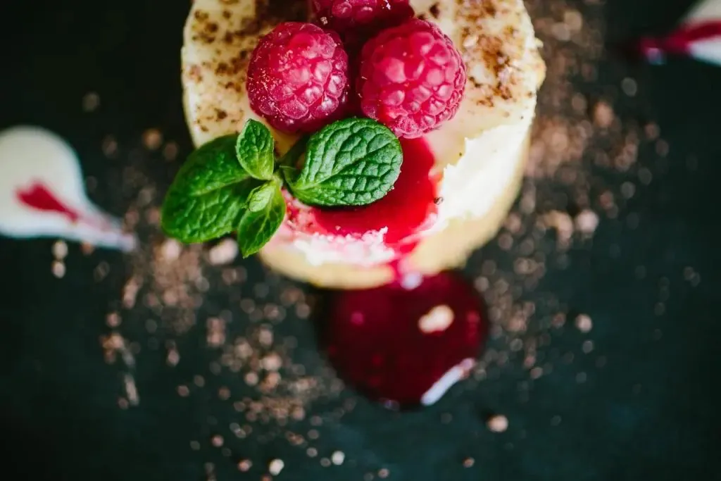 Une vue rapprochée d'un dessert à la crème, décoré de framboises fraîches et de menthe.