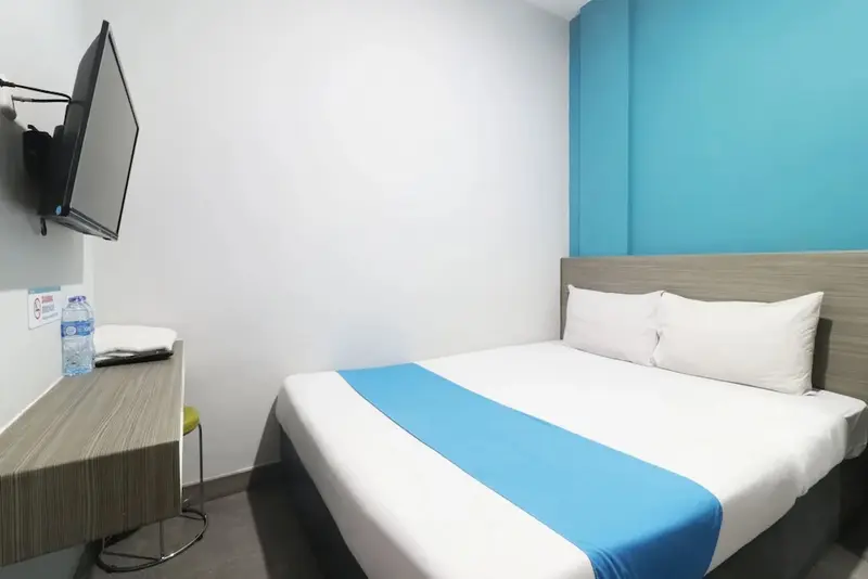 Une chambre lumineuse avec un lit double et un téléviseur mural.