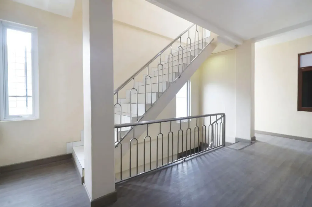 Un escalier en métal blanc mène à l'étage supérieur d'une pièce lumineuse.