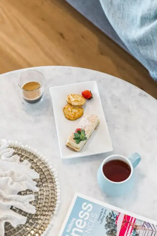 Une table ronde marbree presente un petit-dejeuner compose de viennoiseries, de fruits et de boissons.