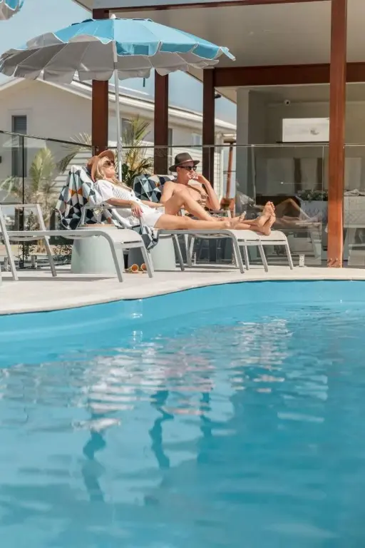 Deux personnes se relaxent au bord d'une piscine ensoleillée.