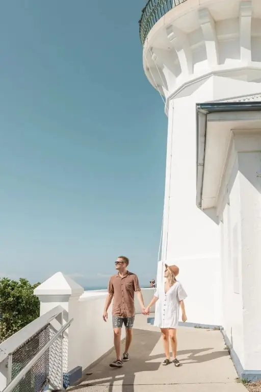 Un couple se promène le long d'un chemin bordé d'un bâtiment blanc.