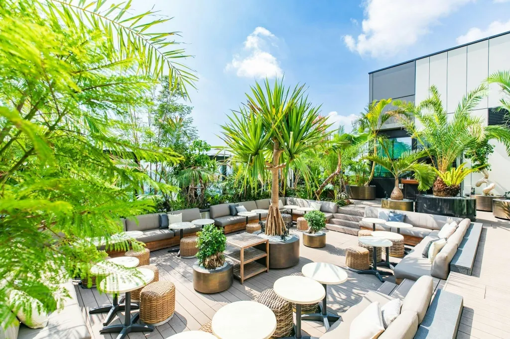 Espace de détente extérieur aménagé avec des canapés, des tables basses et des plantes tropicales.