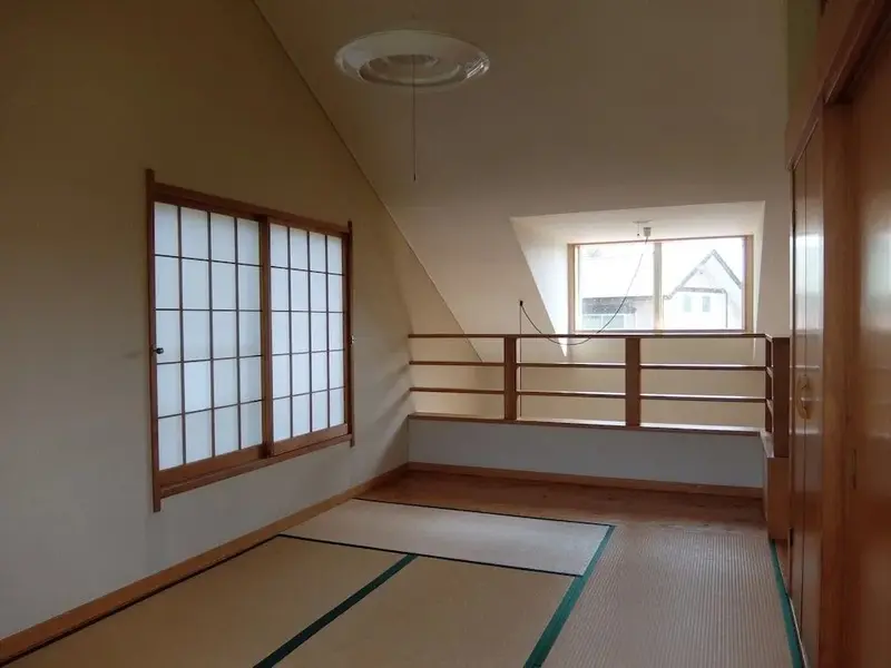 Une pièce lumineuse avec un sol en tatami et une fenêtre traditionnelle.