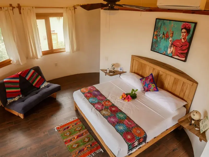 Une chambre lumineuse avec un grand lit décoré de textiles colorés.